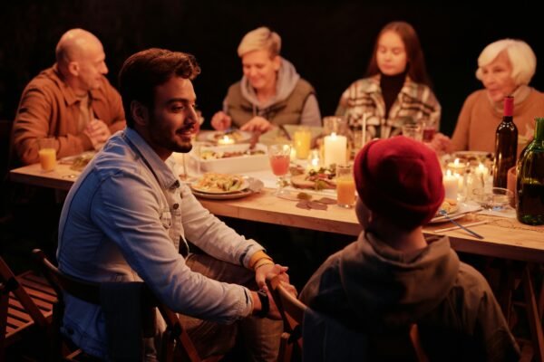 família sentada a mesa, com banquete farto servido, todos estão felizes e conversando